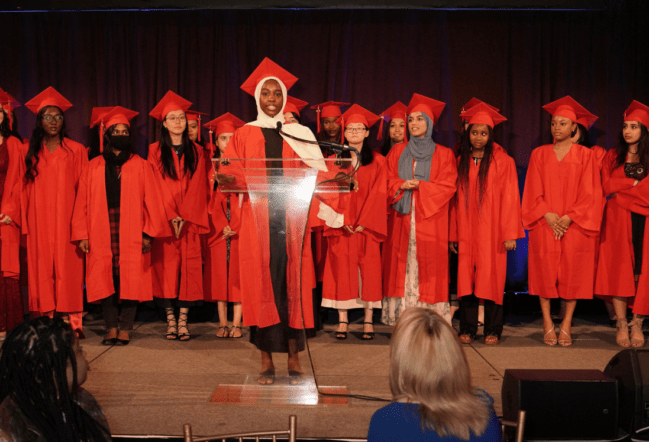 a graduating student podium, with several other graduates behind her